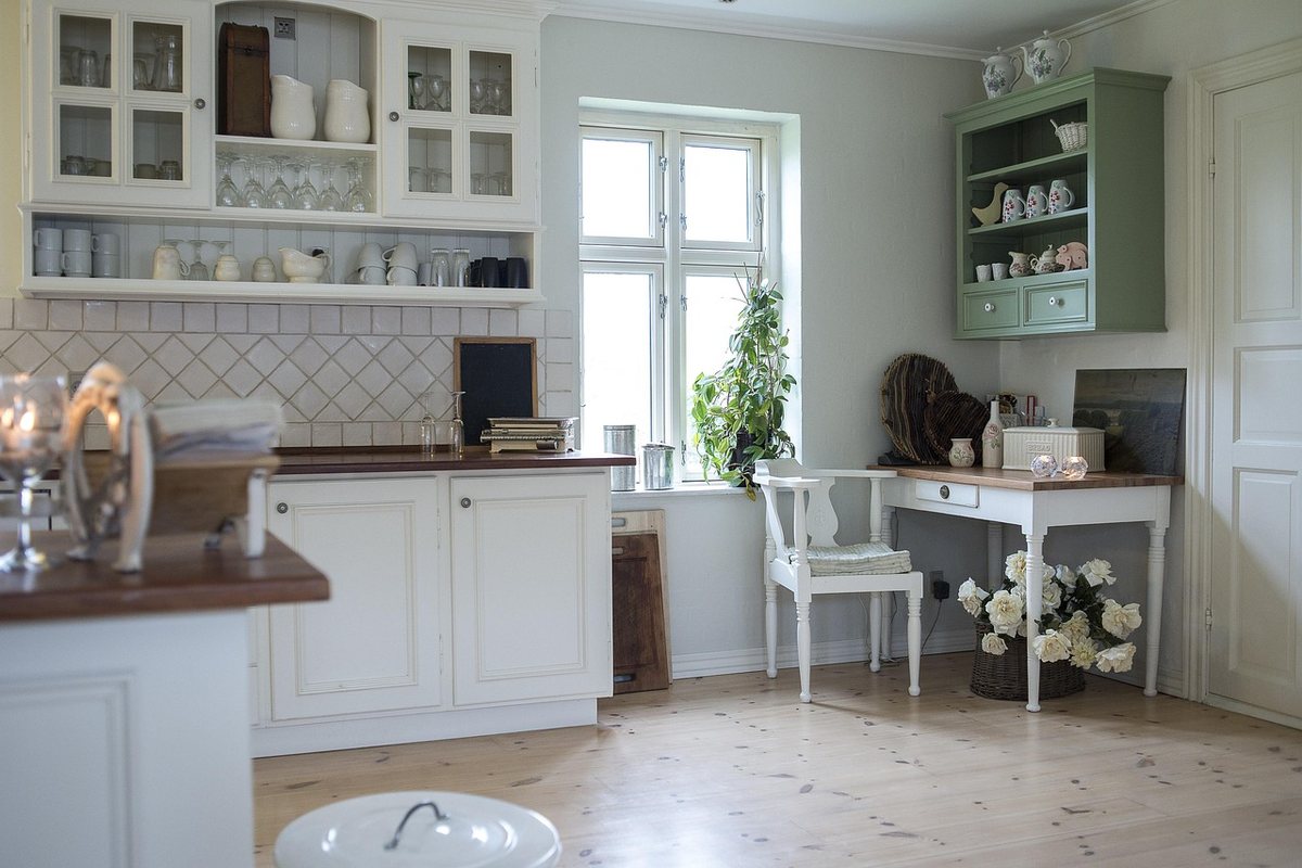 A white desk in a room with fitted cabinetry and drawers along the wall.