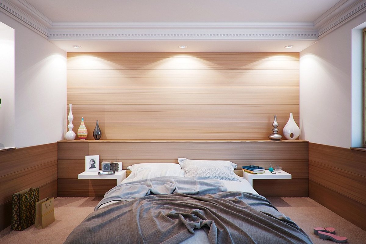 A bedroom with a bed, wood panelling and clear floor along one side.