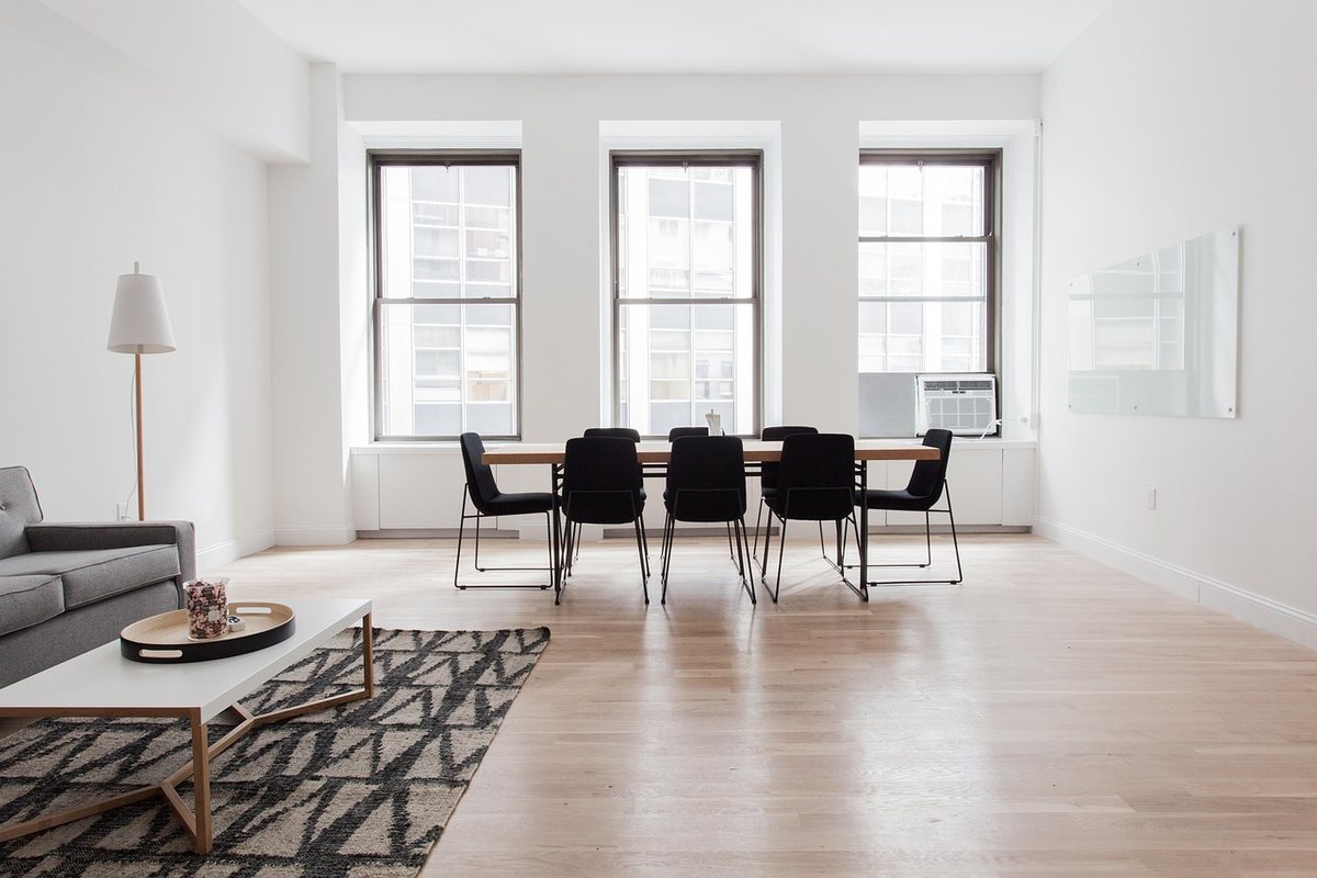 A living room with a round coffee table on a patterned rug and a dining set by the windows.
