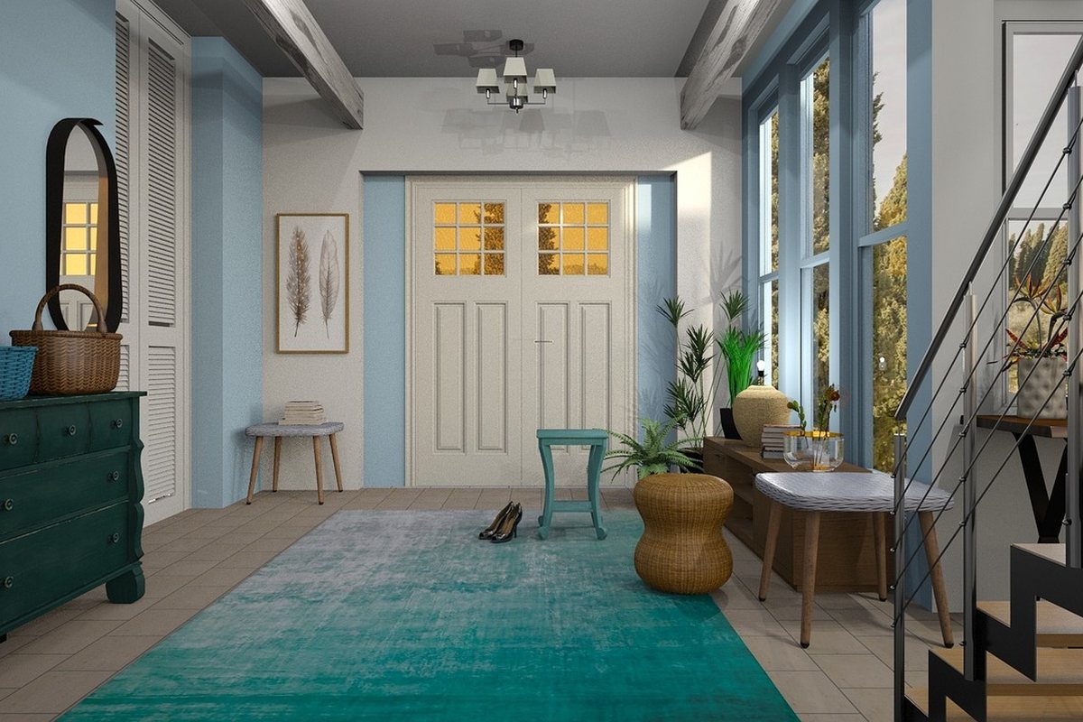 A room with a painted chest of drawers, a rug and a staircase behind.