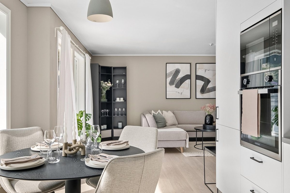 A dining table with grey upholstered chairs in an open-plan room, with a sofa behind it.
