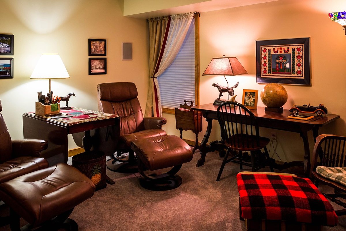 A leather recliner with a matching ottoman, and a second ottoman under a checked blanket.