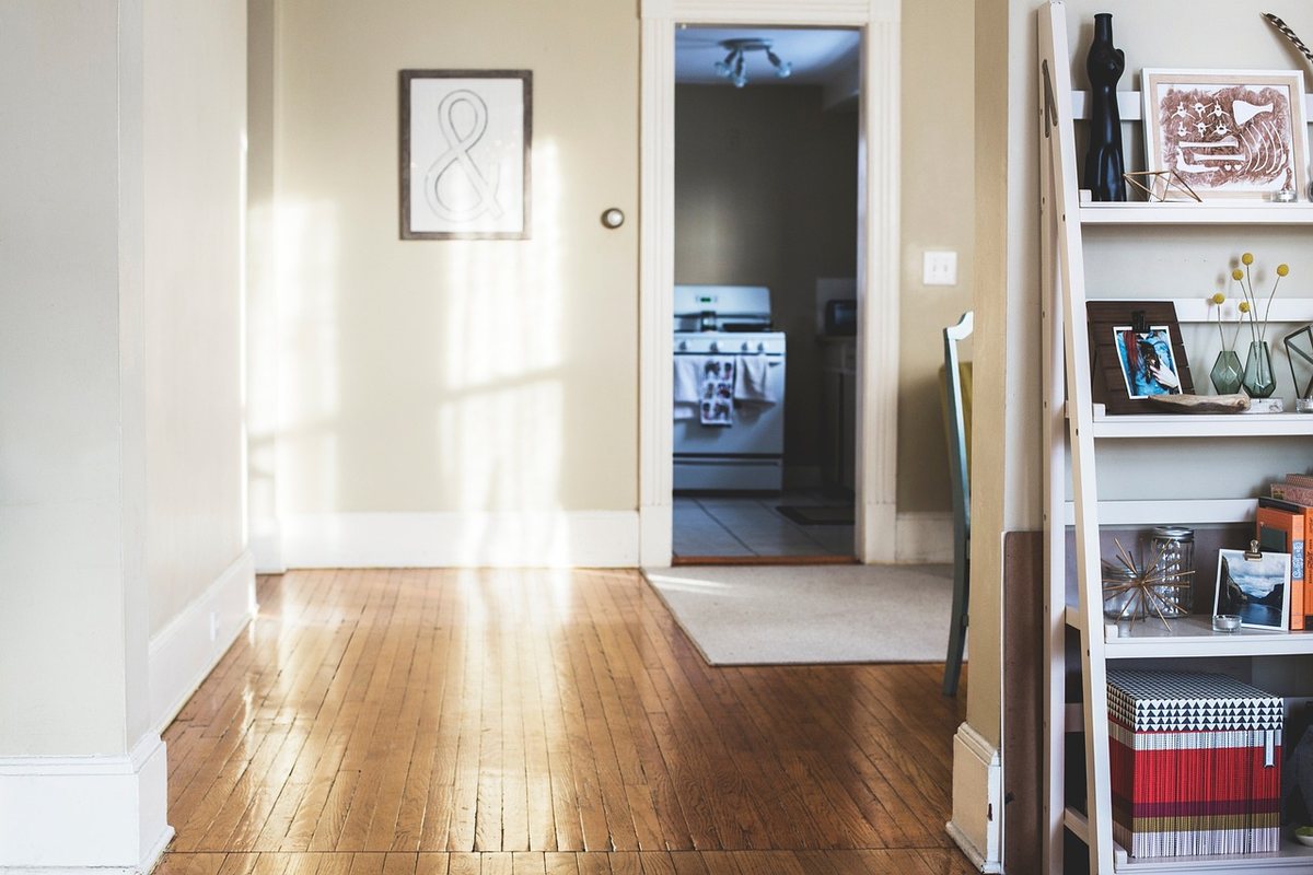 A hallway with a shelving unit against the wall and a doorway beyond.
