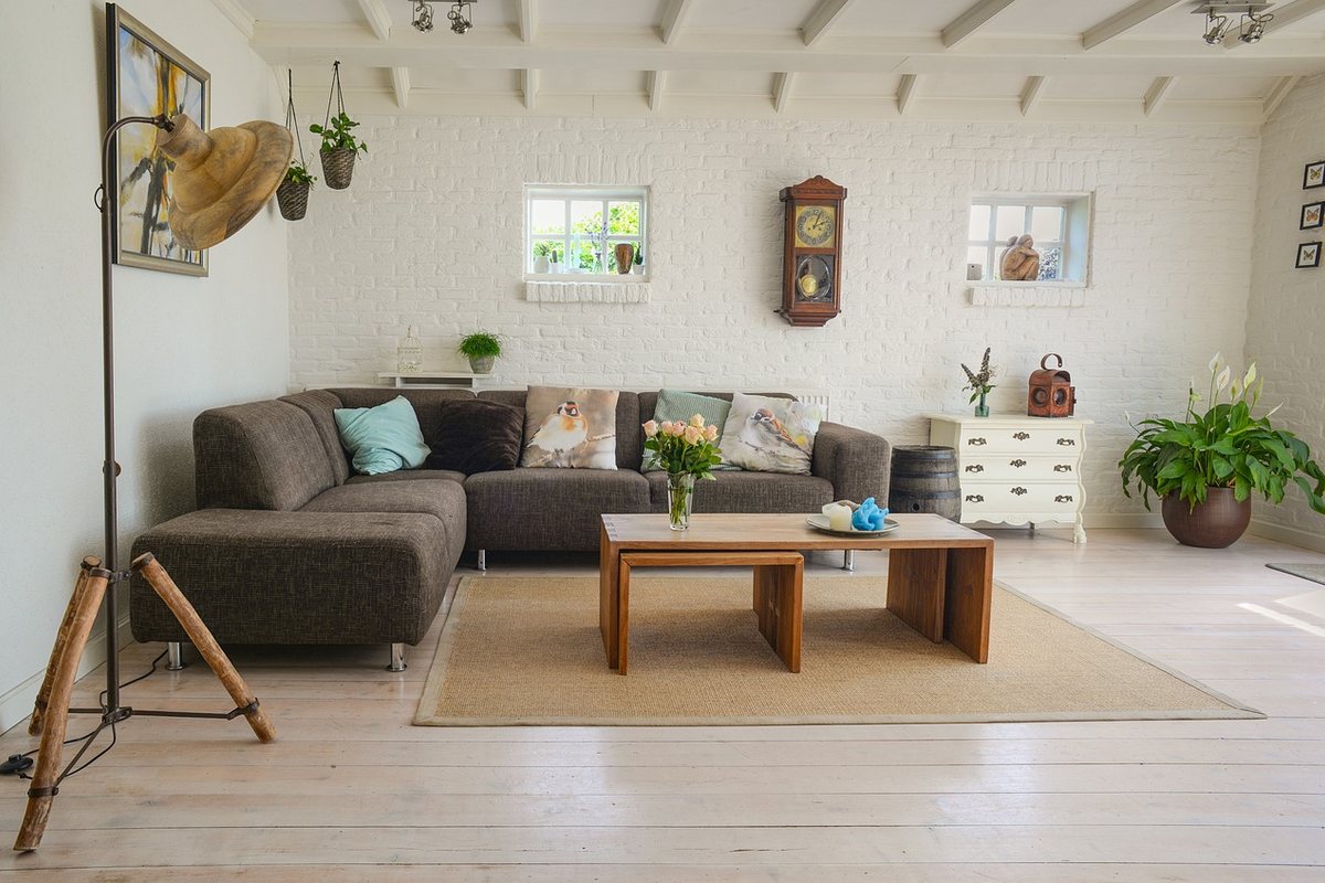 A grey corner sofa facing a low wooden coffee table on a rug in a white room.